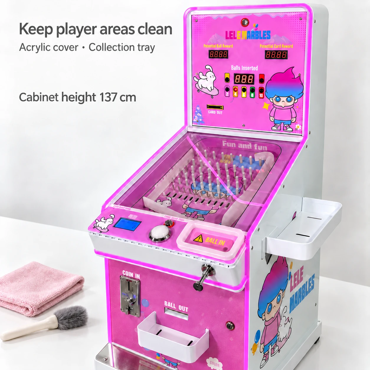 Closed pink cabinet showing its clear cover and collection trays beside a folded cloth and soft brush.